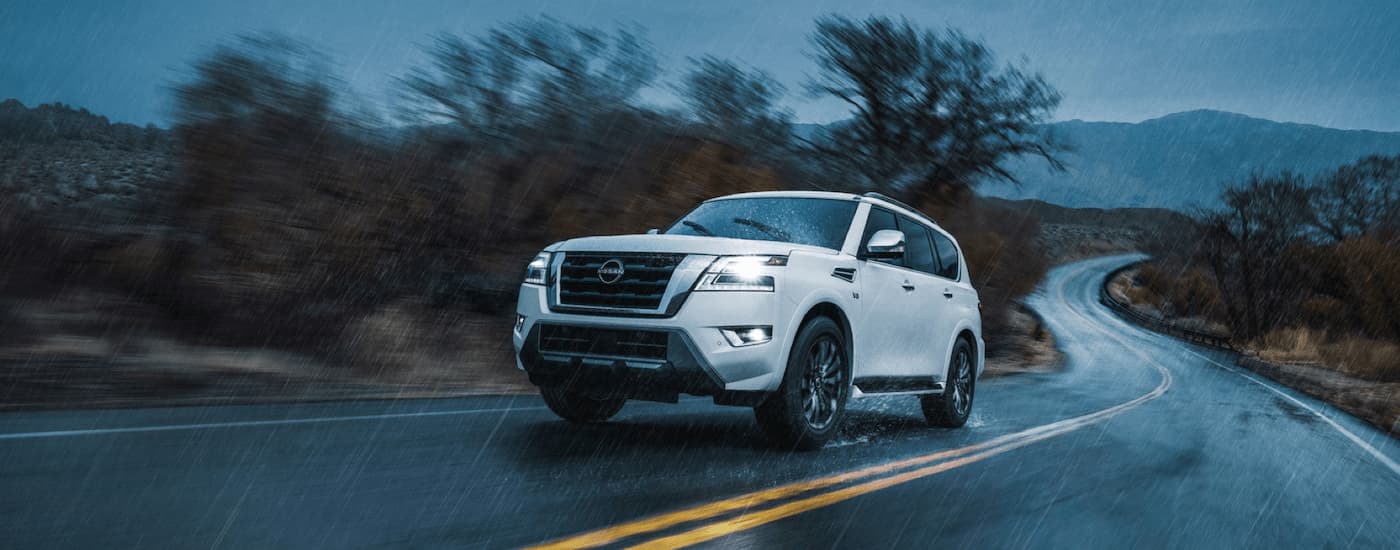 A white 2022 Nissan Armada is shown driving during a rainstorm.