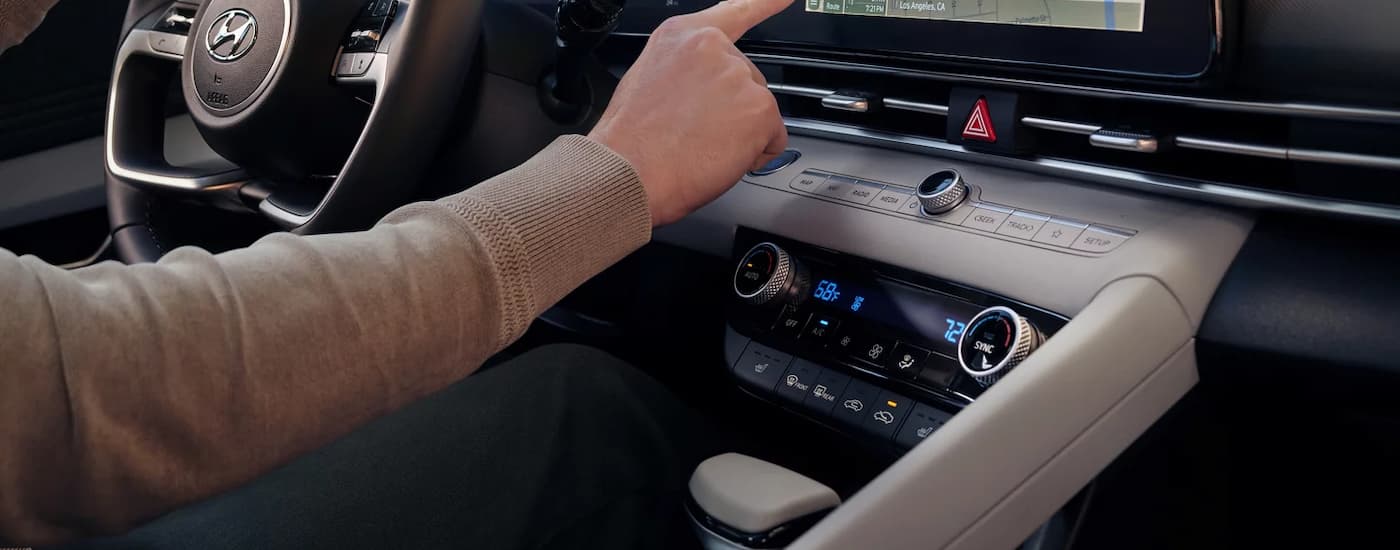 A person is shown using the infotainment screen in a 2023 Hyundai Elantra.