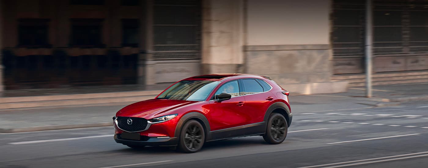 A red 2023 Mazda CX-30 for sale is shown on a city street.