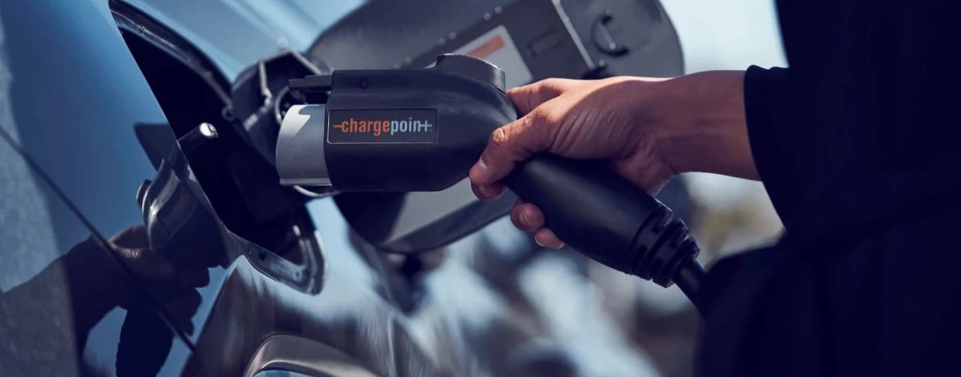 A person is shown plugging charging a black  2023 Hyundai Tucson Hybrid Limited.