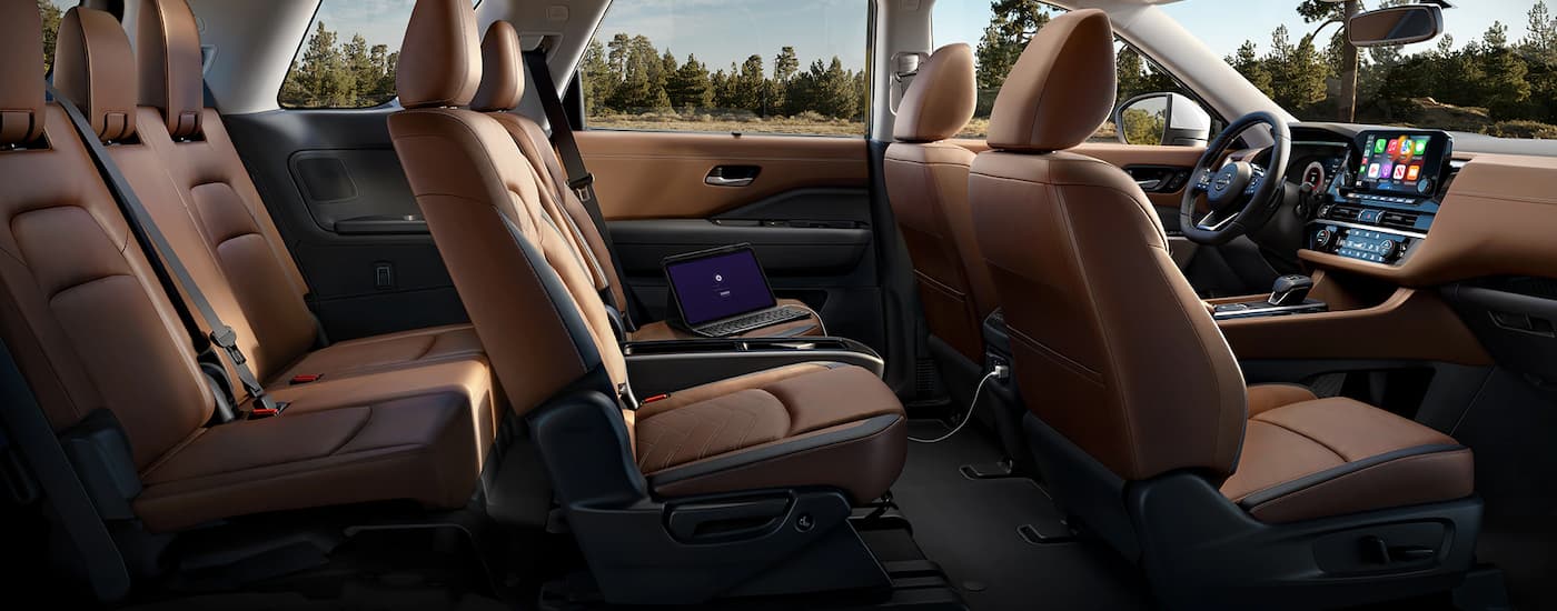 The brown interior of a 2023 Nissan Pathfinder shows three rows of seating.