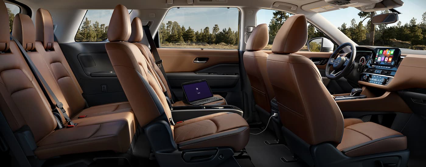 A tan 2023 Nissan Pathfinder shows three rows of seating.
