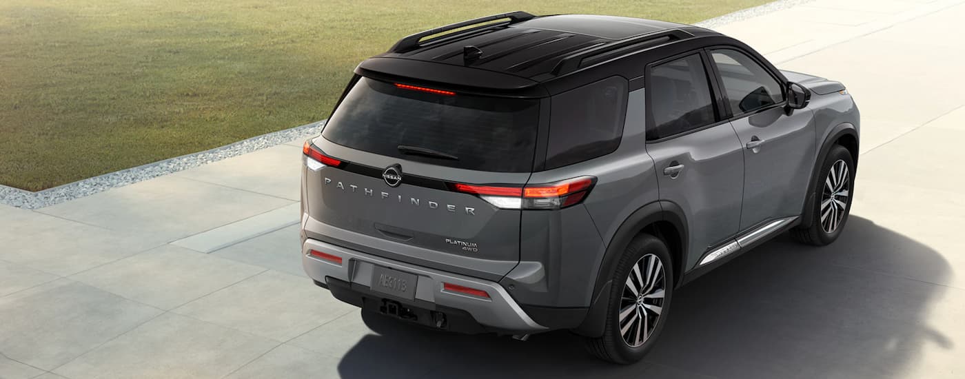 A grey 2023 Nissan Pathfinder is shown from the rear driving on an open road.