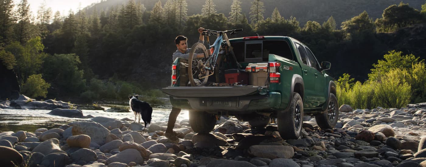 A popular Nissan Frontier for sale, a green 2023 Nissan Frontier is shown parked next to a river. 