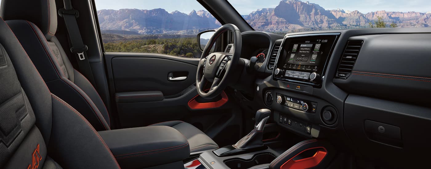 The grey interior of a 2023 Nissan Frontier shows the front seats and steering wheel.