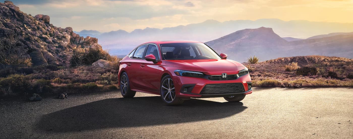 A red 2023 Honda Civic Touring is shown parked in a lot overlooking a mountain view.