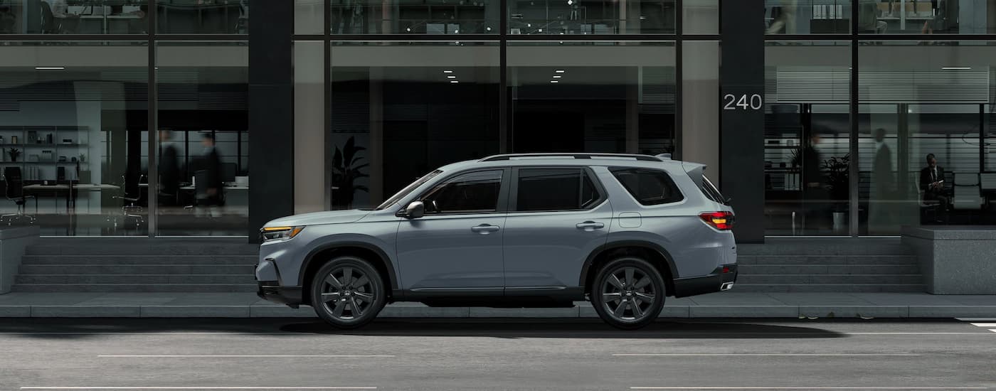A grey 2023 Honda Pilot parked on the side of a city street.