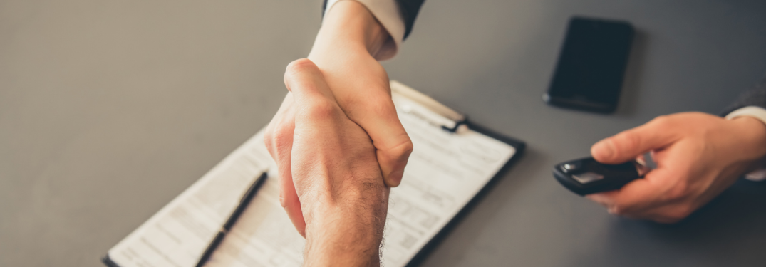 Two people handshaking over paperwork