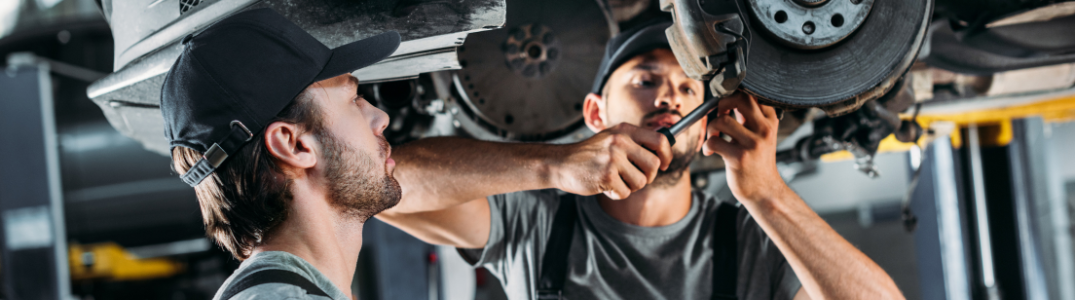 Two men working on the underside of a car
