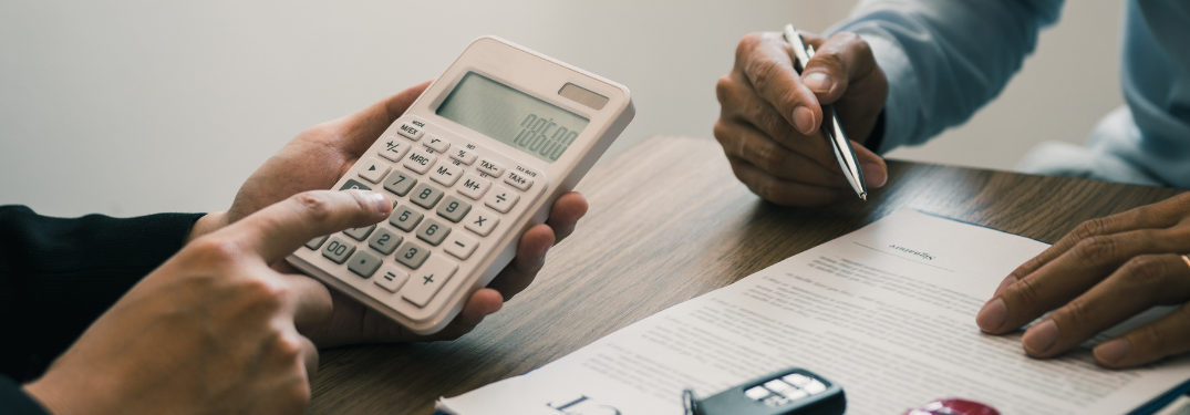 A man using a calculator while another works on paperwork