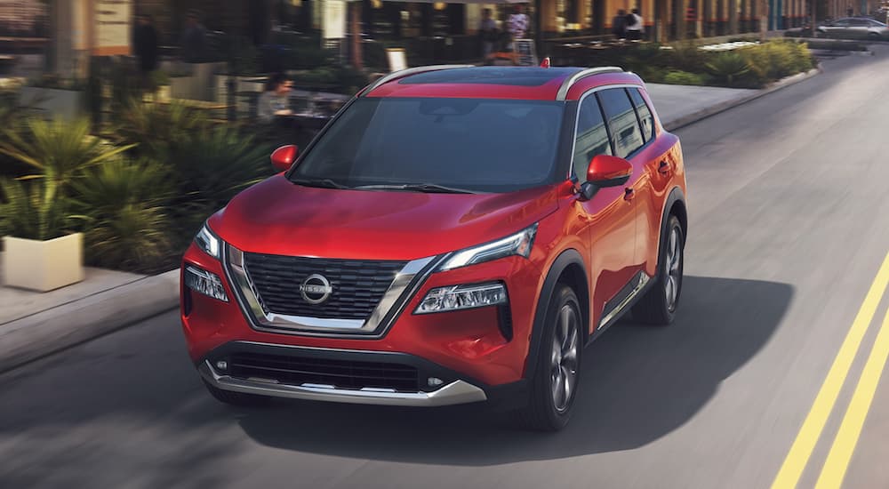A red 2023 Nissan Rogue is shown from the front driving on an open road.