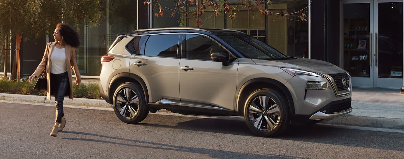 A tan 2022 Nissan Rogue is shown from the side parked on a city street.