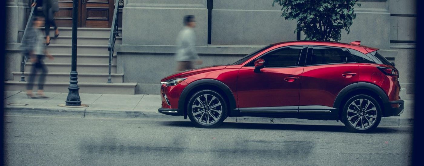 A red  2019 Mazda CX-3 is shown on a city street after looking at used SUVs for sale.