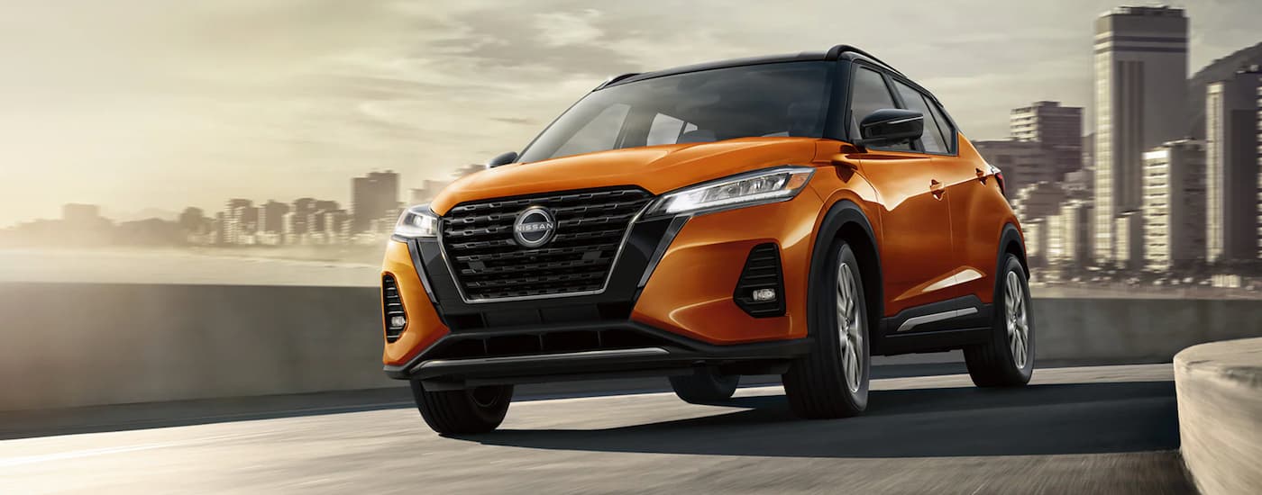 A popular Nissan SUV, an orange 2023 Nissan Kicks, is shown rounding a city corner.