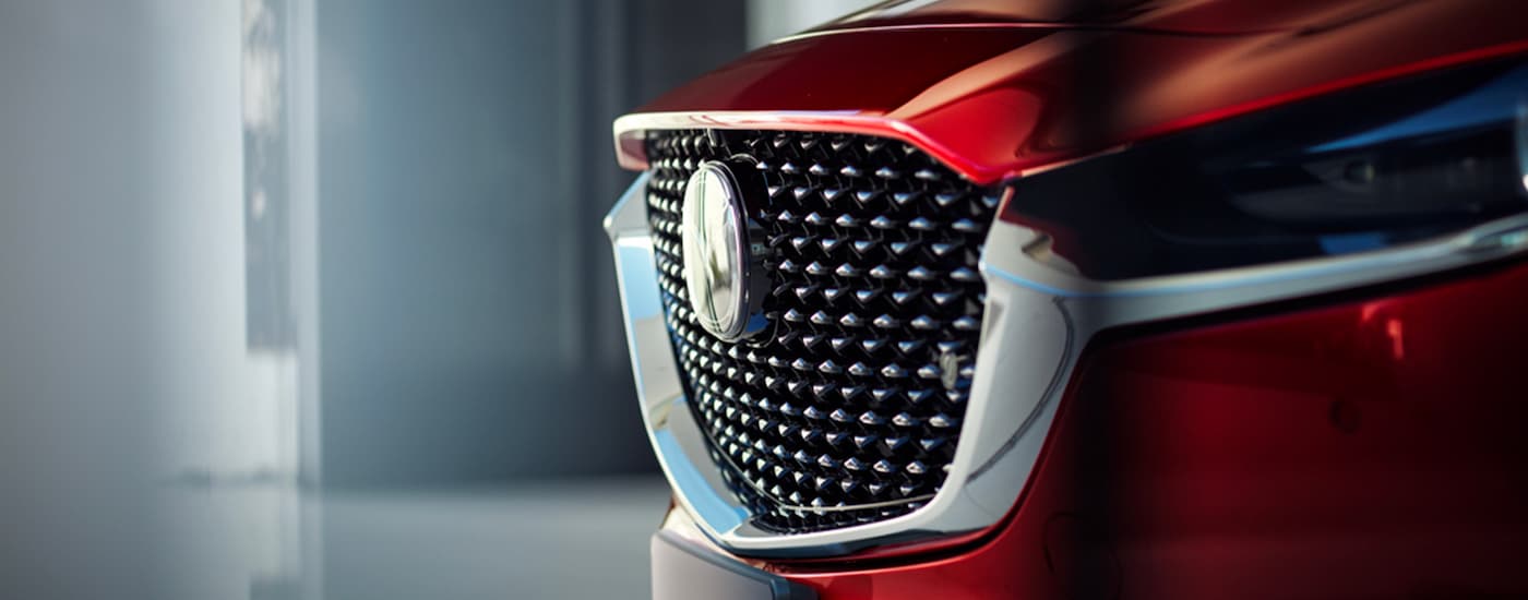 A close up shows the chrome grille on a red 2023 Mazda CX-30 parked at a Shoreline Mazda dealer.