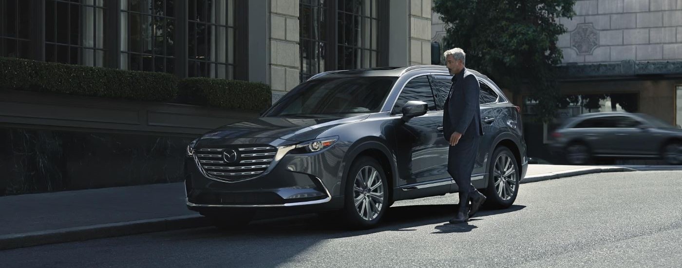 A grey 2023 Mazda CX-9 is shown parked on a city street.