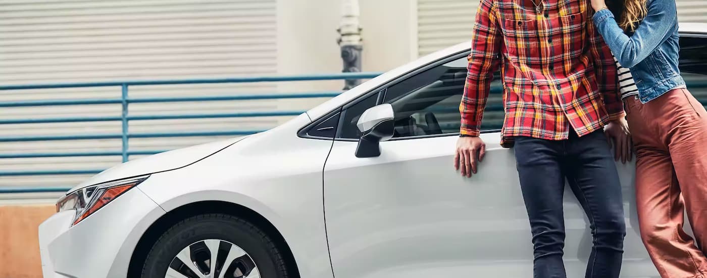 People are shown leaning against a white 2022 Toyota Corolla.