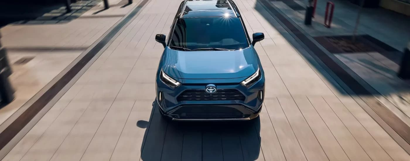 A blue 2022 Toyota RAV4 is shown from a high angle driving on wide city street.