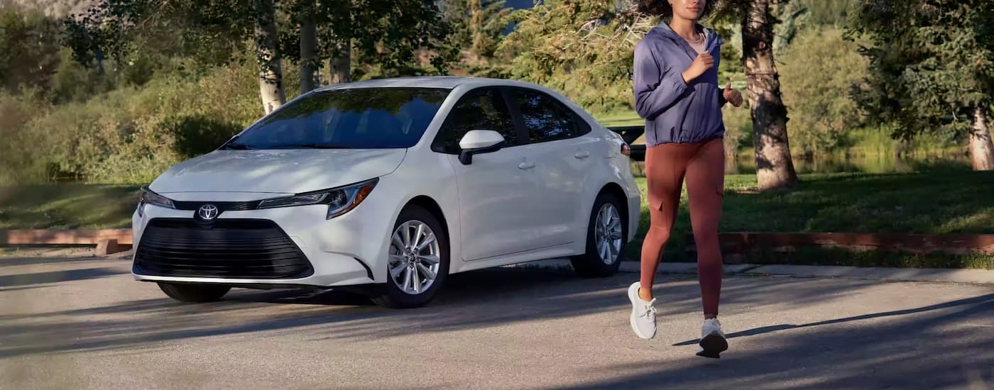 A person is shown jogging near a white 2023 Toyota Corolla LE parked in an empty lot.