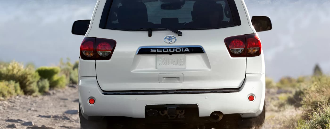 Rear view of a white 2022 Toyota Sequoia parked on a rocky dirt road.