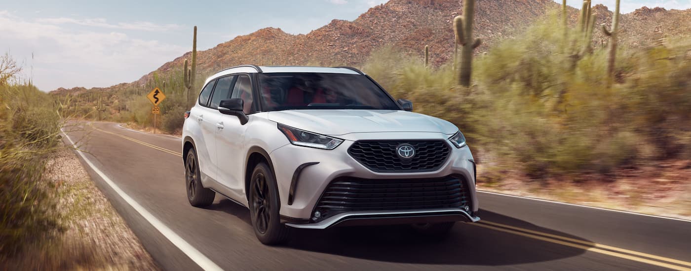A white 2023 Toyota Highlander XSE AWD drives on a winding desert road.