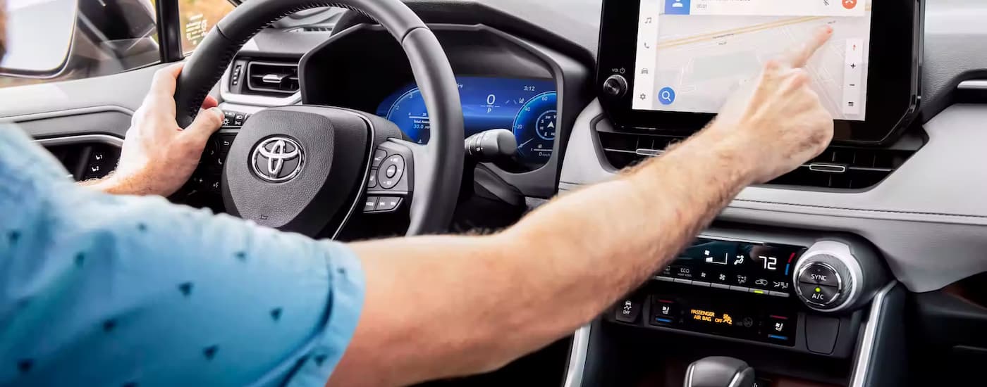Seen from inside the cabin, a driver uses the navigation screen in a 2023 Toyota RAV4