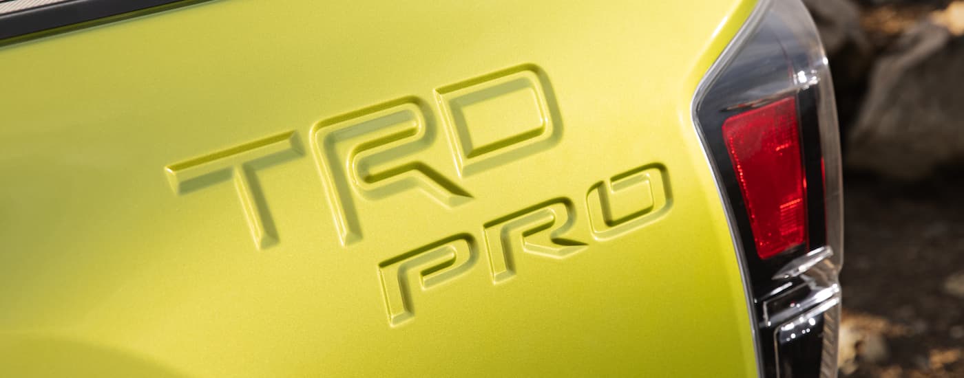 A close up of the TRD PRO badge on the back of a lime green 2021 Toyota Tacoma TRD Pro.