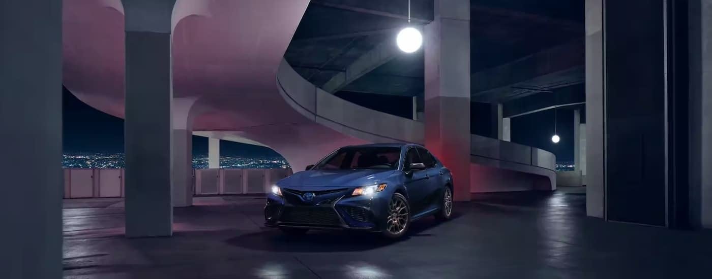 A blue 2022 Toyota Camry Nightshade parked in a modern concrete garage at night.