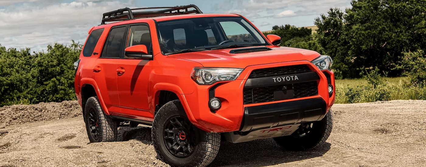 An orange 2023 Toyota 4Runner TRD Pro is shown parked on a sandy lot.