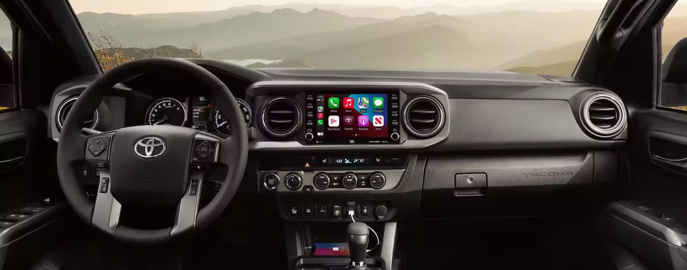 Interior view of a 2023 Toyota Tacoma, showing infotainment display and mountains outside.