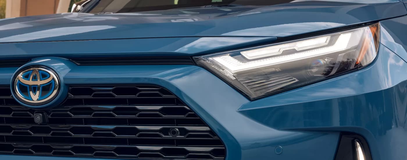 A close-up of the driver side headlight on a blue 2022 Toyota RAV4.