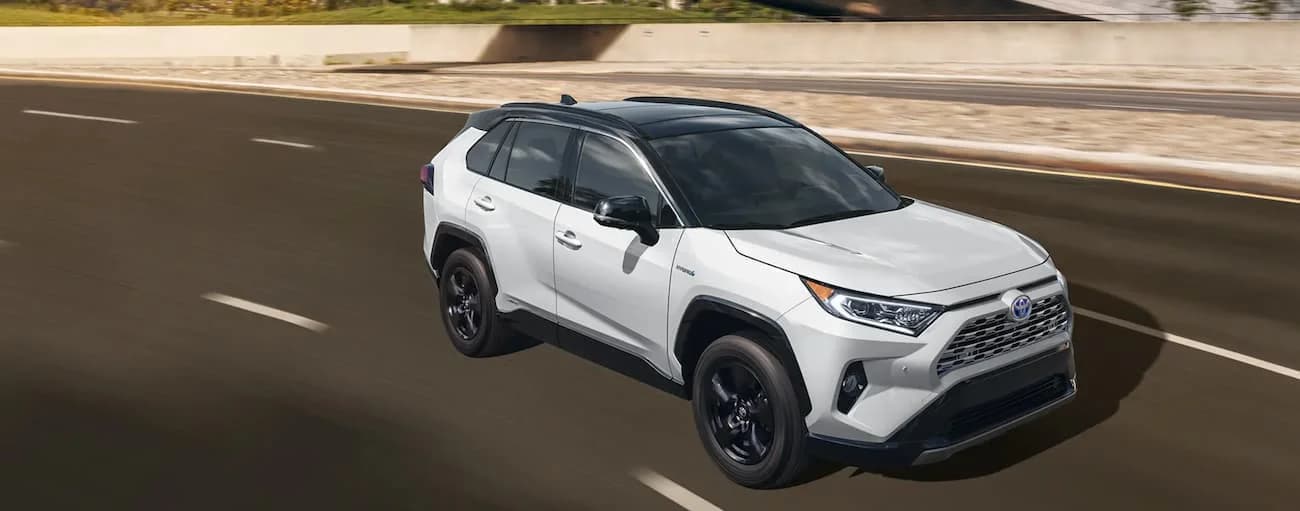 A white 2020 Toyota RAV4 Hybrid driving on an open road.