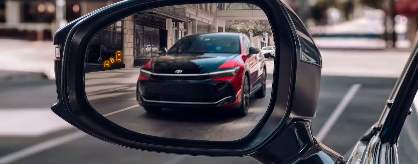 A black and red 2023 Toyota Crown is shown in the rearview mirror of another vehicle.