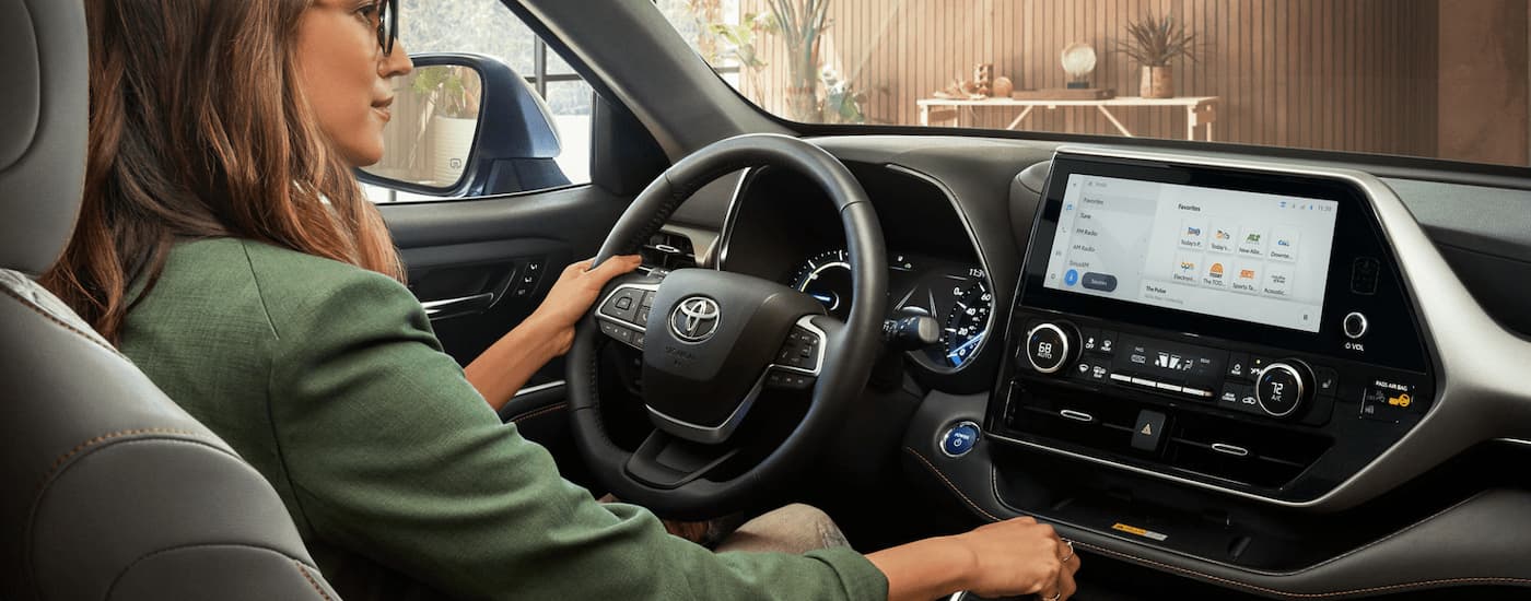 A woman is shown driving a 2023 Toyota Highlander.