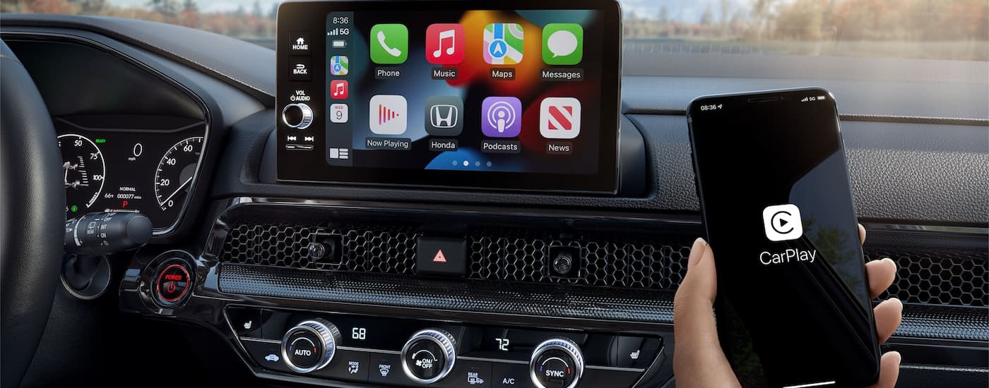 A passenger using Apple CarPlay on their smartphone while riding in a 2023 Honda CR-V Hybrid.