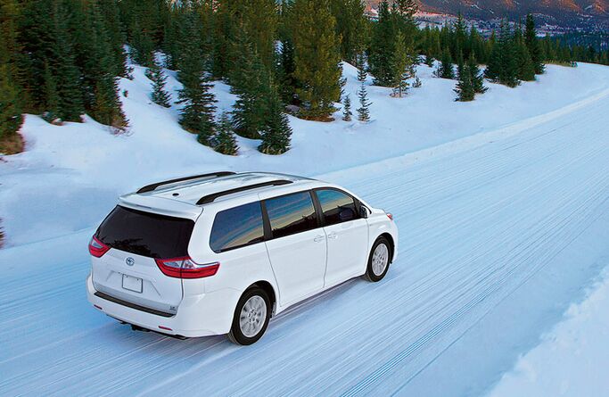 2017 Toyota Sienna white exterior rear passenger side driving in snow