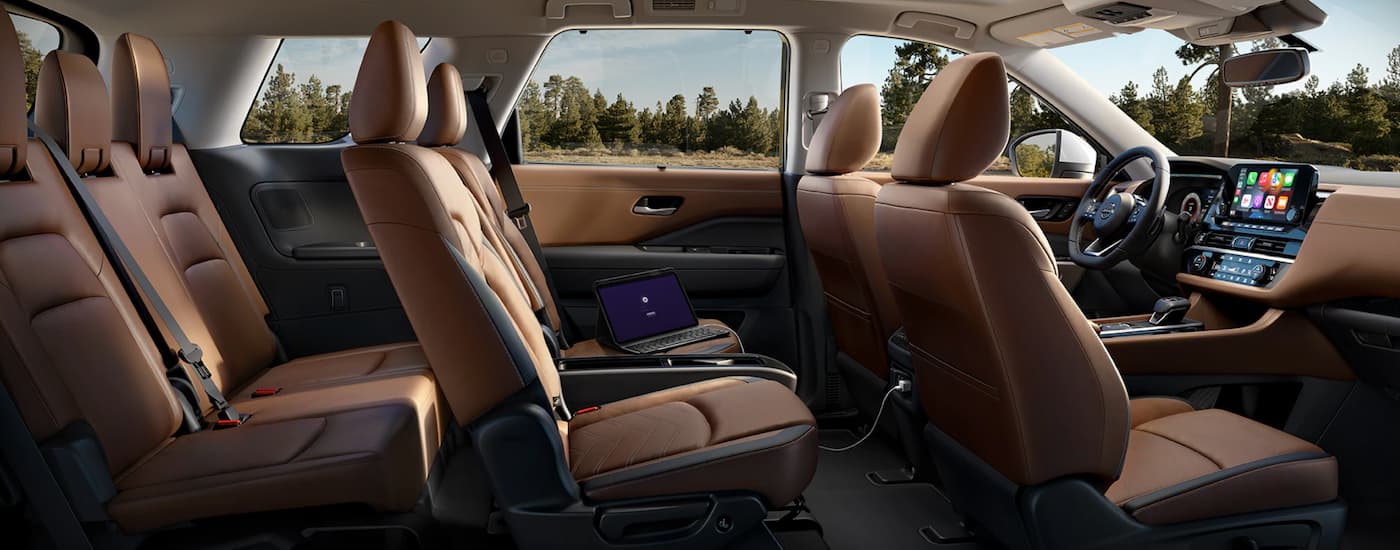 The brown interior of a 2023 Nissan Pathfinder shows three rows of seating.