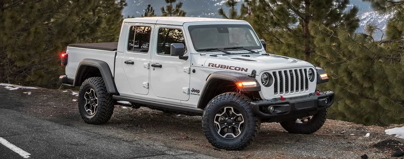 A white 2023 Jeep Gladiator is shown from the side parked in the mountains.