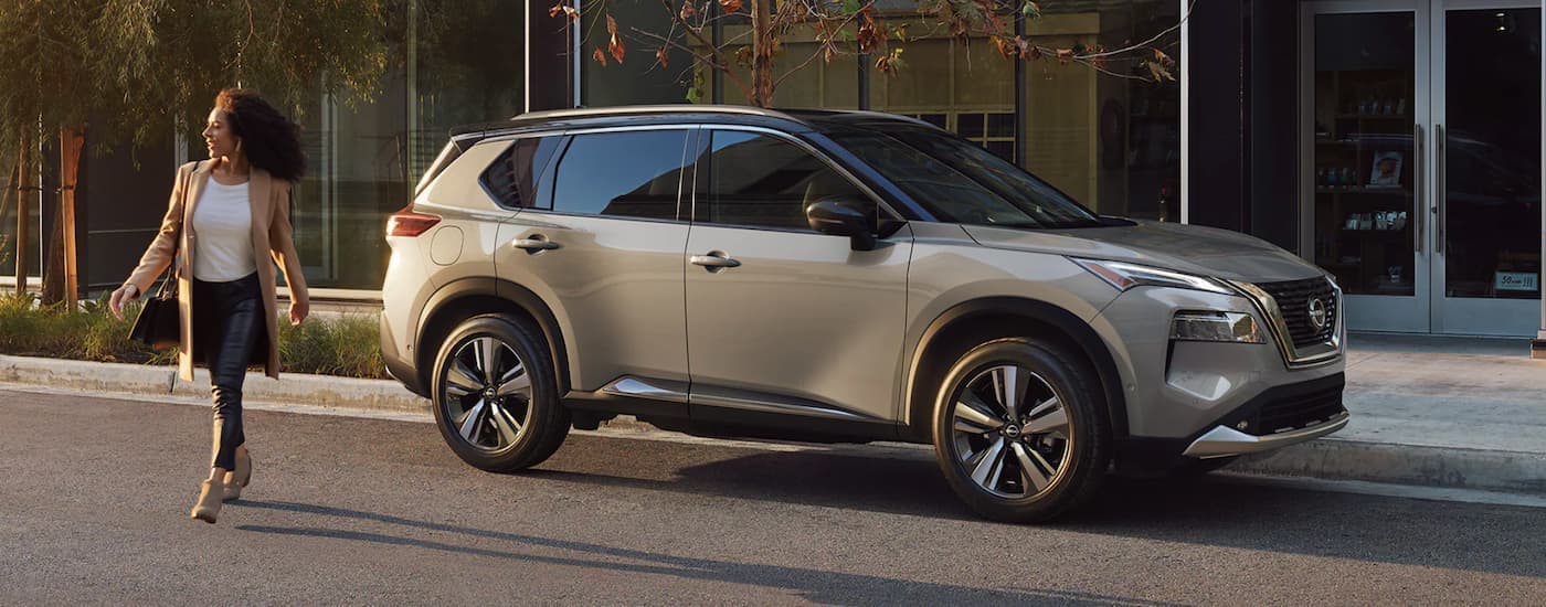 A tan 2022 Nissan Rogue is shown from the side parked in front of a building.