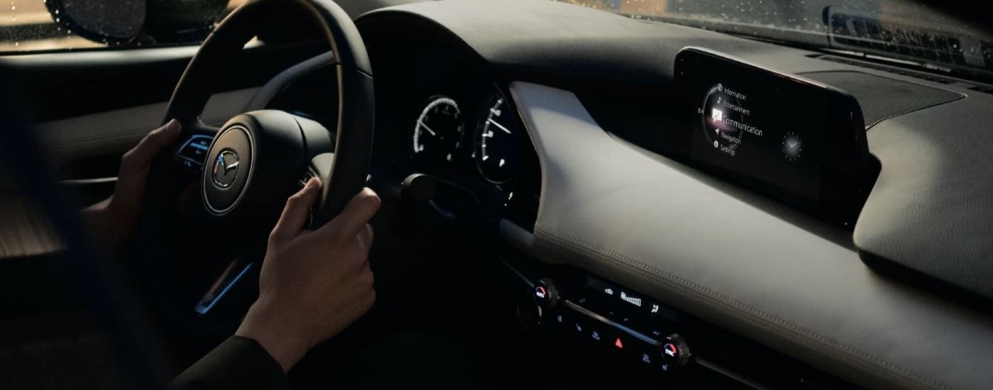 A person is shown steering a 2023 Mazda3.