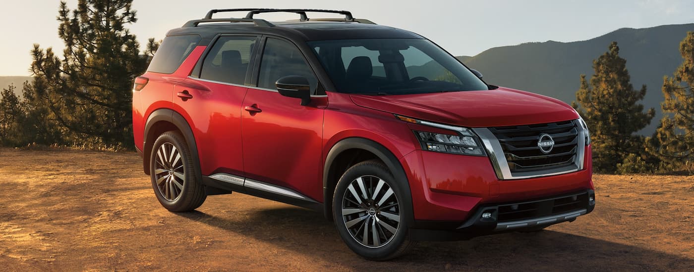 A red 2023 Nissan Pathfinder is shown from the side parked in the mountains.
