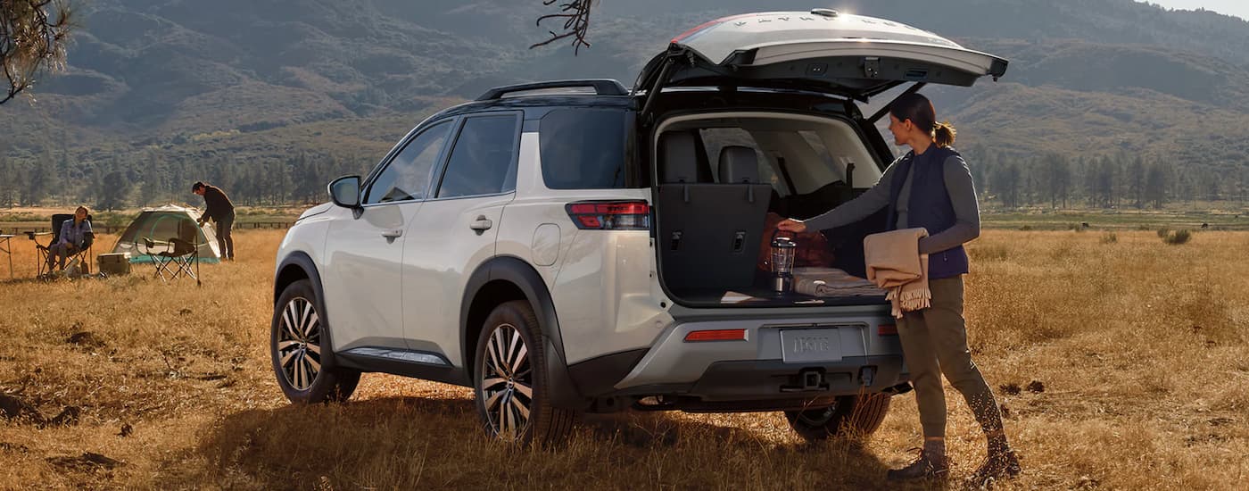 A popular Nissan Pathfinder for sale, a white 2023 Nissan Pathfinder, is shown parked in a field.