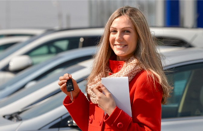 Woman holding keys in front of car