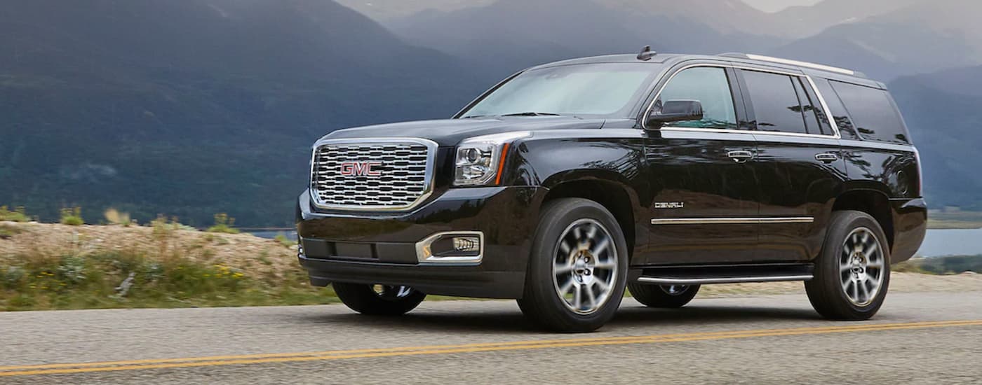 A black 2020 GMC Yukon Denali is shown driving on an open road.