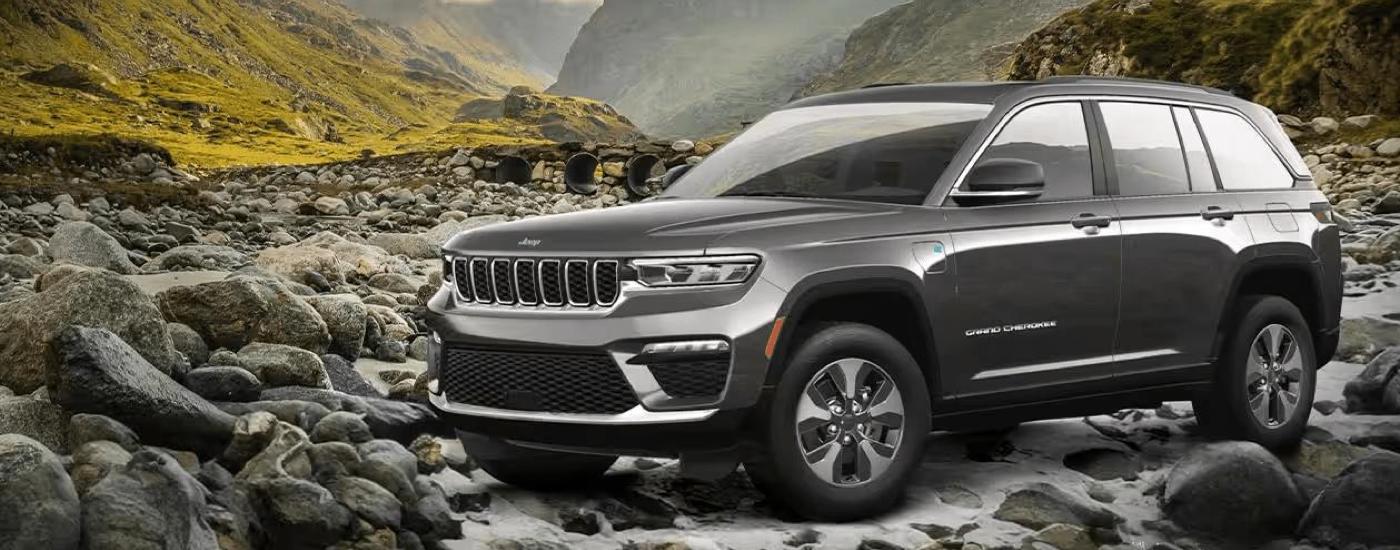 A grey 2023 Jeep Grand Cherokee 4xe for sale is shown parked on a dry river bed.