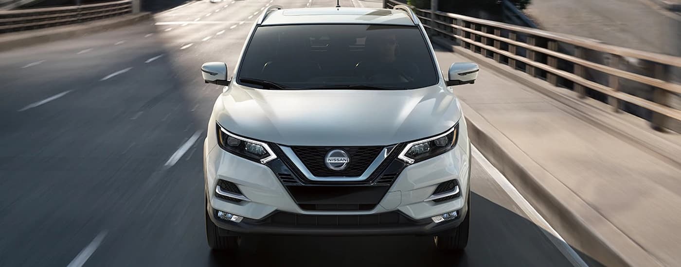 A white 2022 Nissan Rogue is shown from the front driving on a highway.