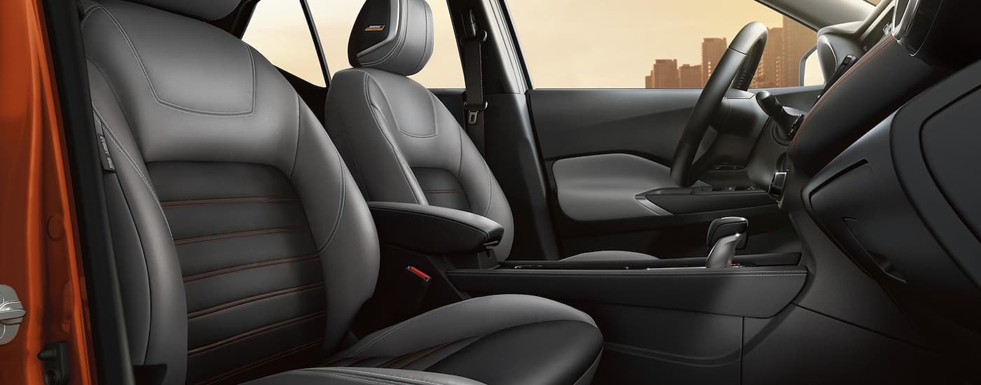 The black interior of an orange 2022 Nissan Kicks shows the front seating and center console.