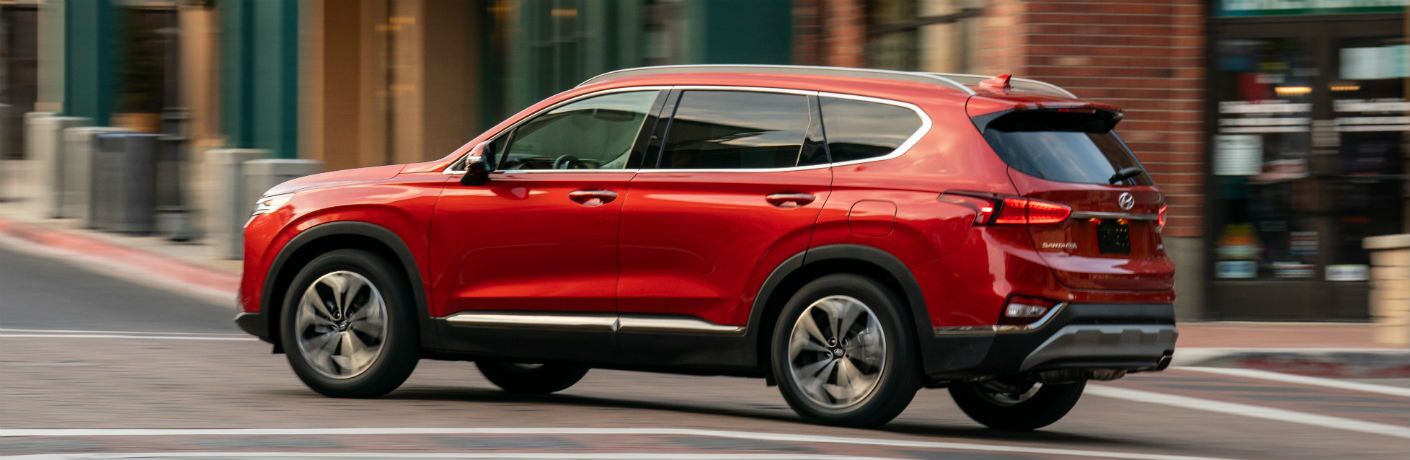 Red 2020 Hyundai Santa Fe rolls around a deserted city corner.