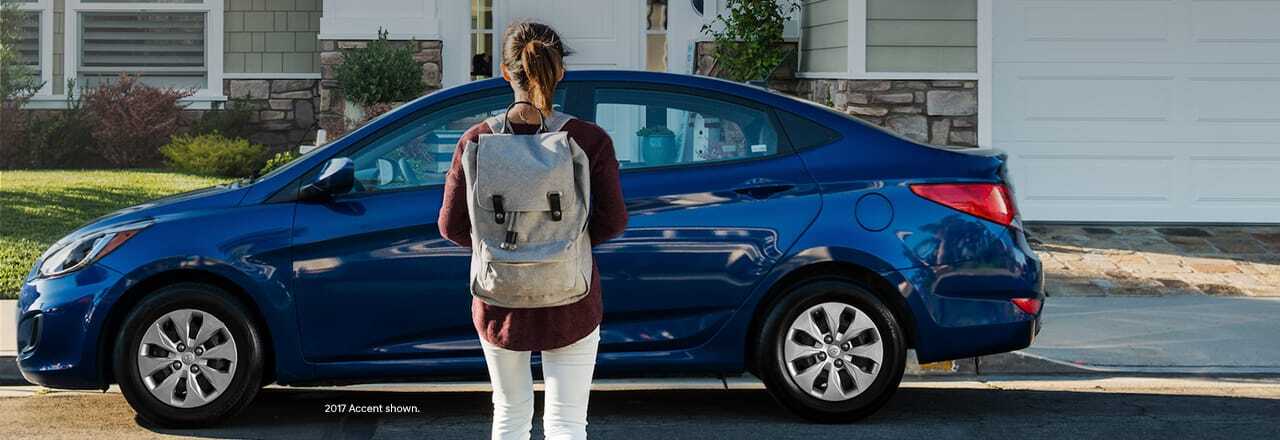 Girl with backpack looking at car
