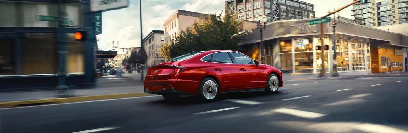 A red 2023 Hyundai Sonata Hybrid on the city road. 